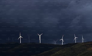 a group of windmills on a hill under a dark sky