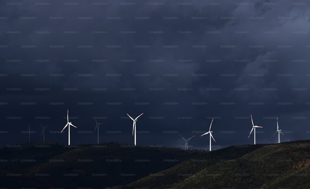 um grupo de moinhos de vento em uma colina sob um céu escuro