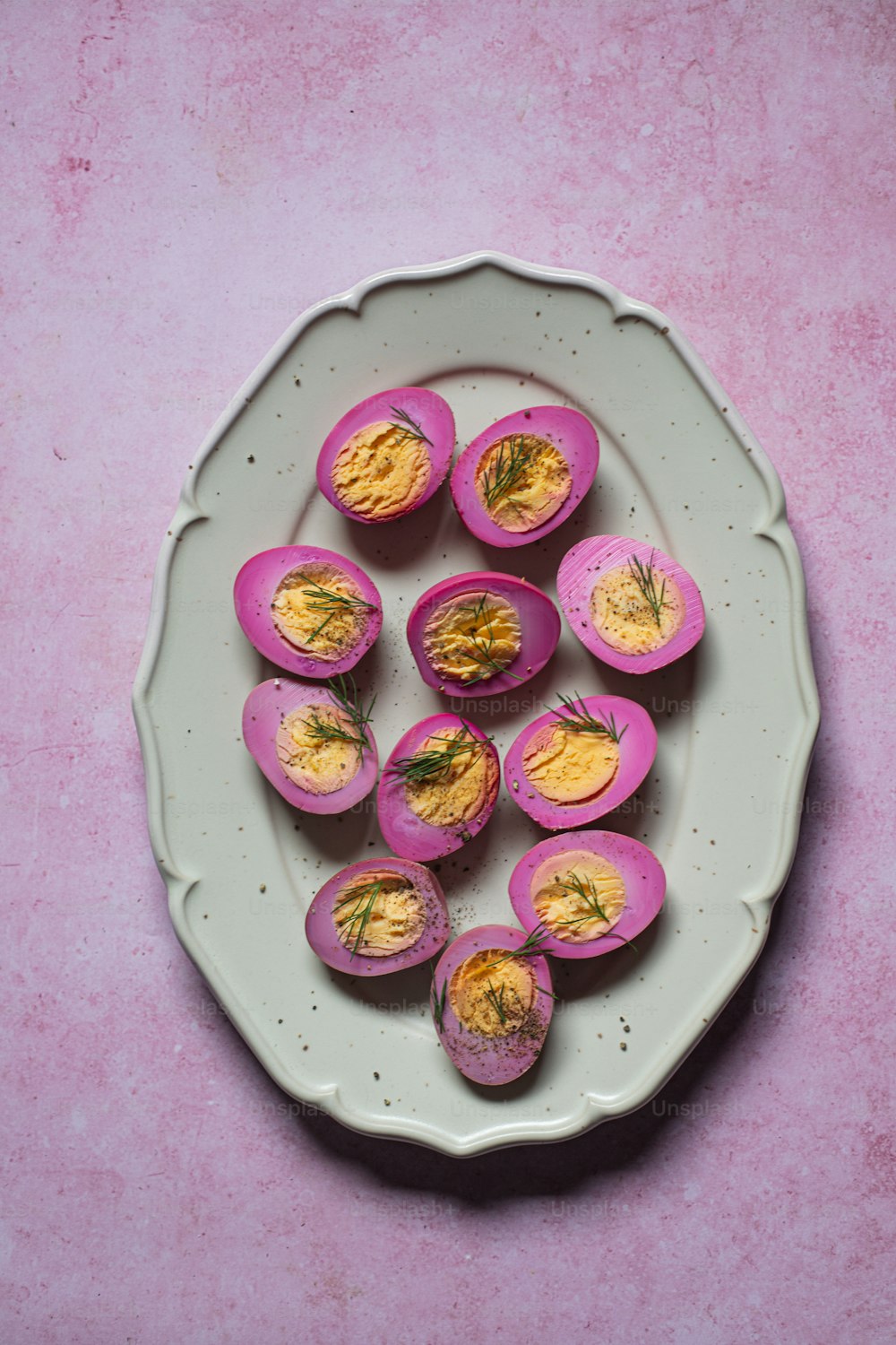 a plate of deviled eggs on a pink table