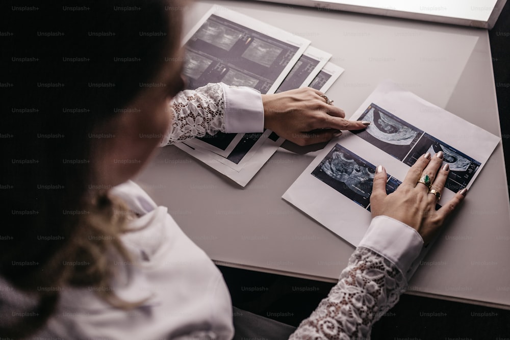 a woman sitting at a table working on a piece of paper