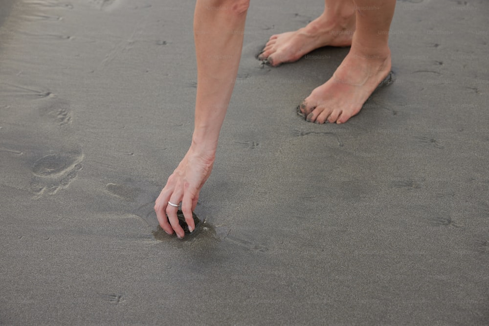 une personne debout sur une plage, les pieds dans le sable