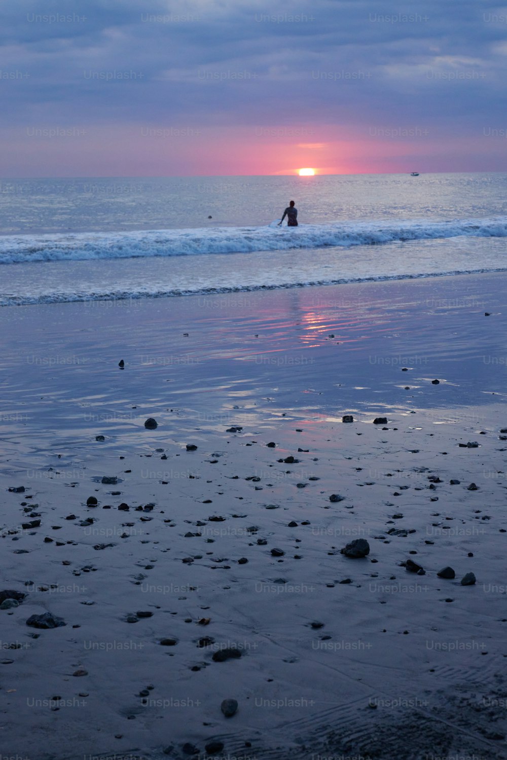 a person riding a horse on a beach at sunset