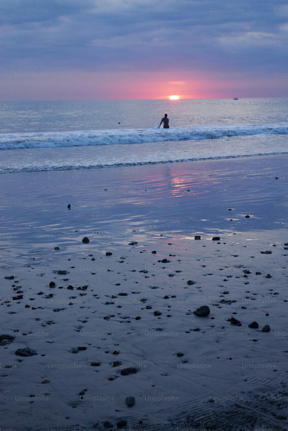 une personne à cheval sur une plage au coucher du soleil