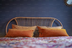 ein Bett mit zwei orangefarbenen Kissen und einer blauen Wand