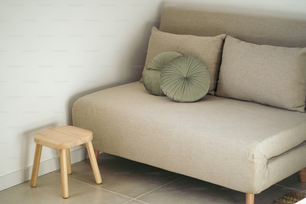a couch with a pillow on it next to a stool