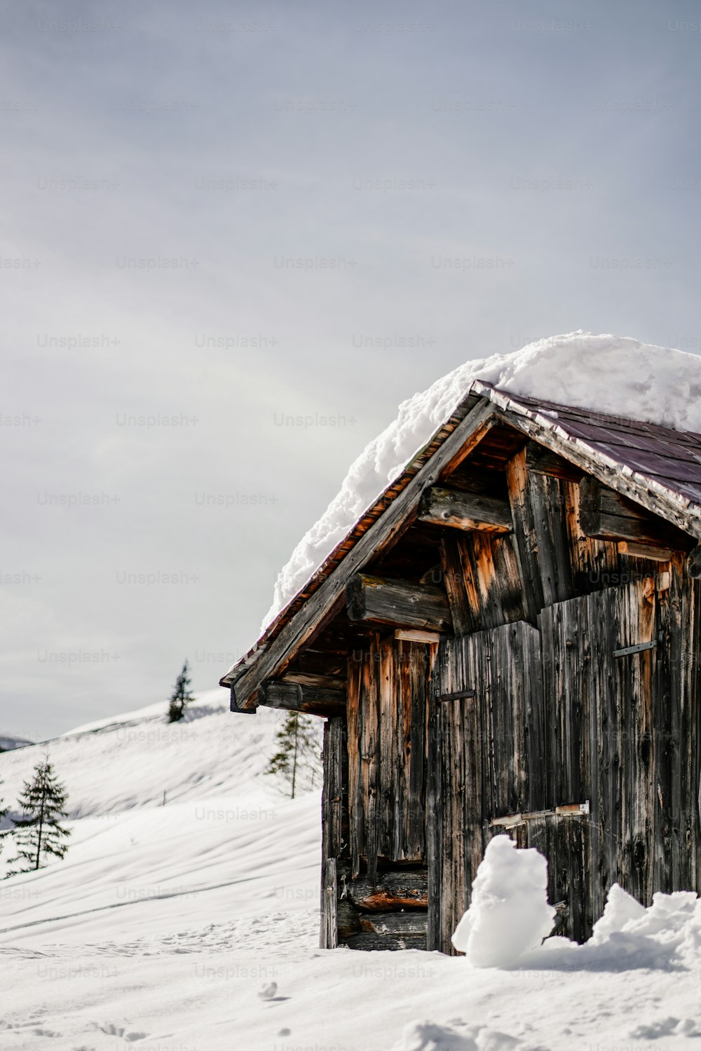 ein kleines Holzgebäude mit Schnee darüber