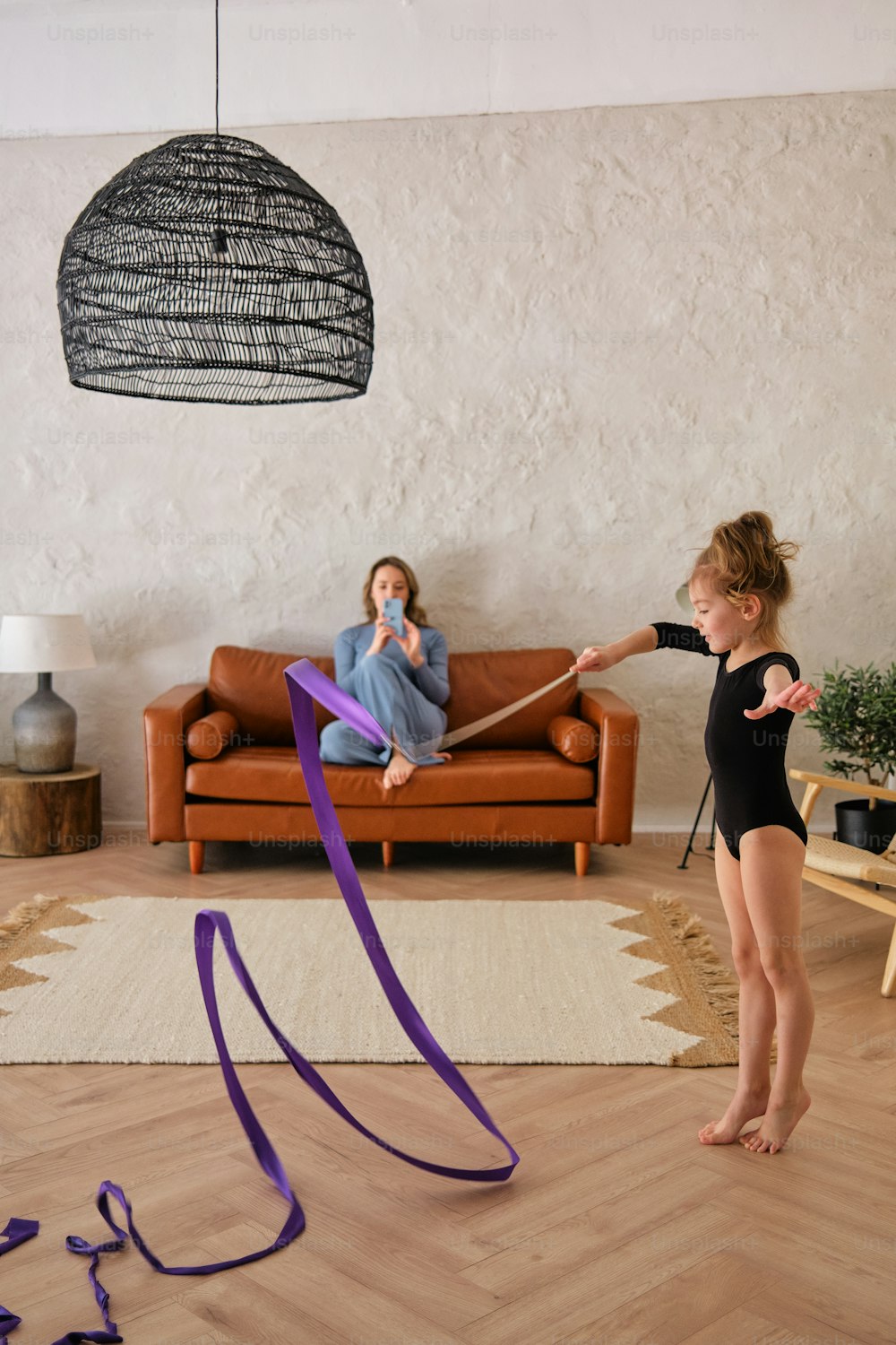 a girl is playing with a purple ribbon in a living room