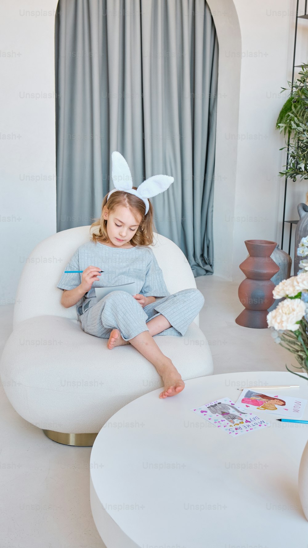 a little girl sitting in a chair with a bunny ears on her head