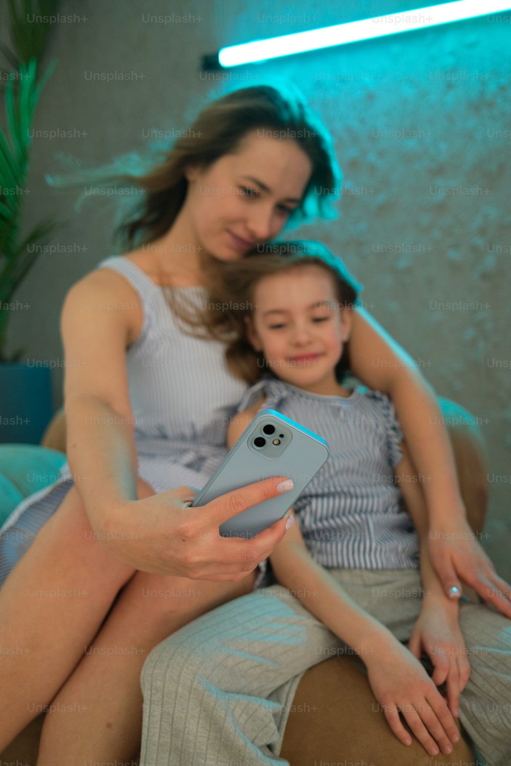 a woman holding a cell phone next to a little girl