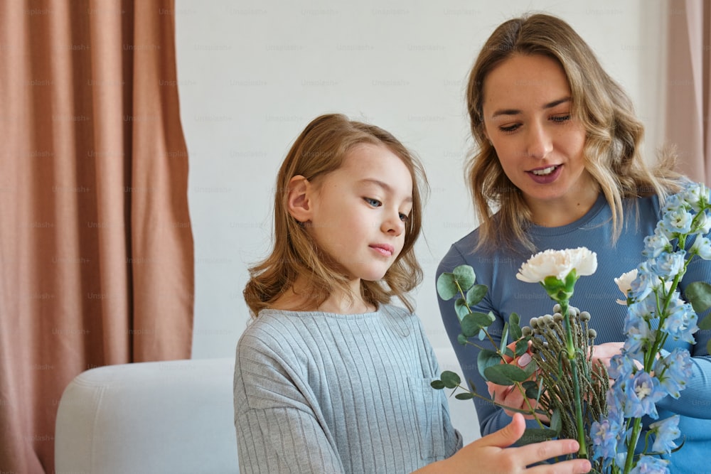 a woman and a girl are looking at a bouquet of flowers