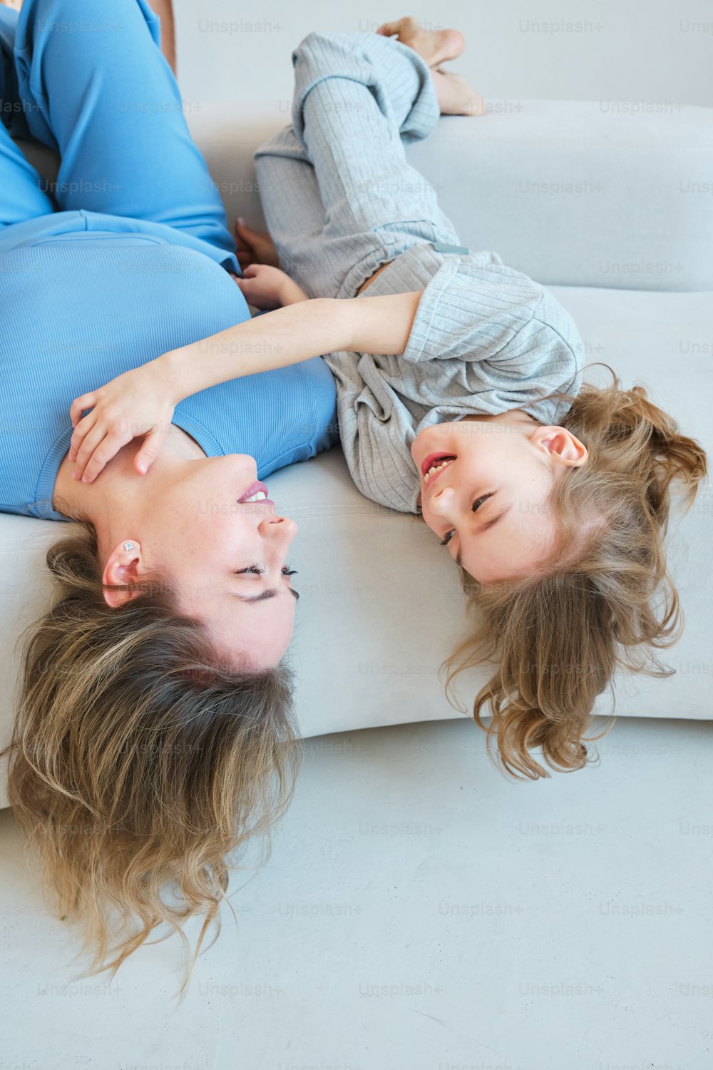 a woman and a girl laying on a couch
