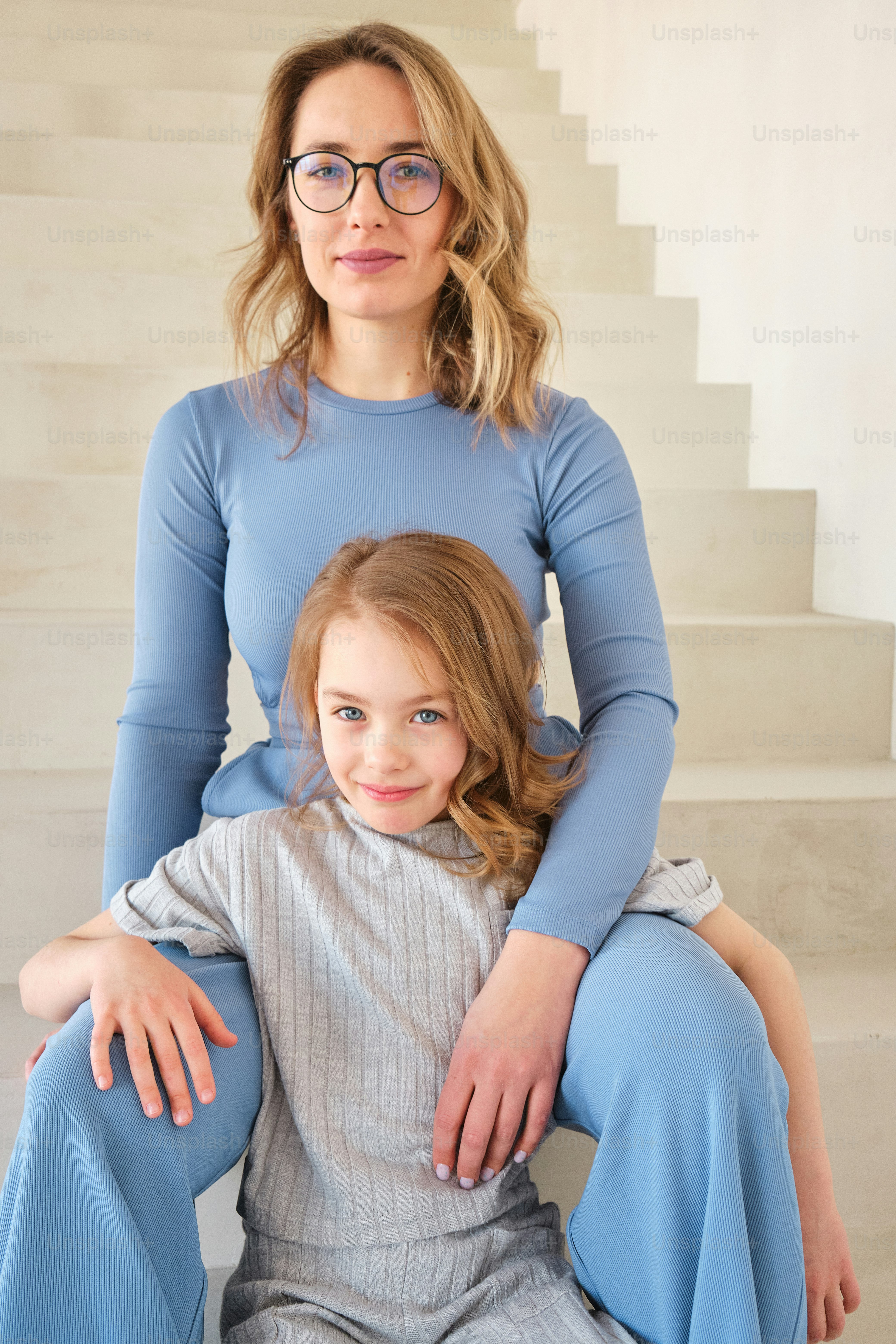 a woman sitting next to a little girl