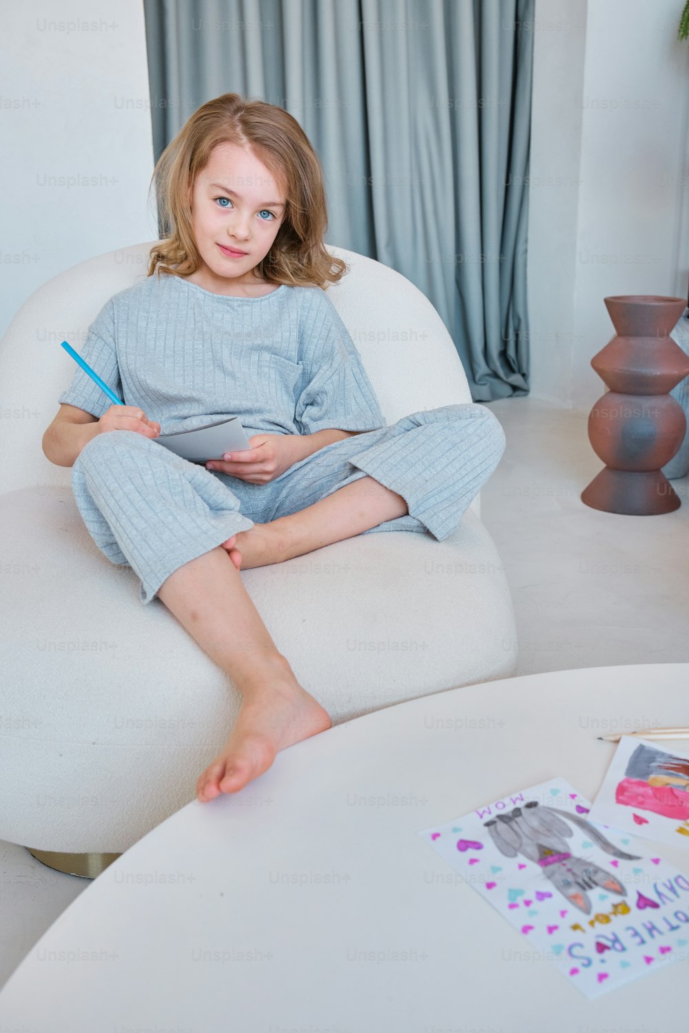 a girl sitting on a chair with a pencil in her hand