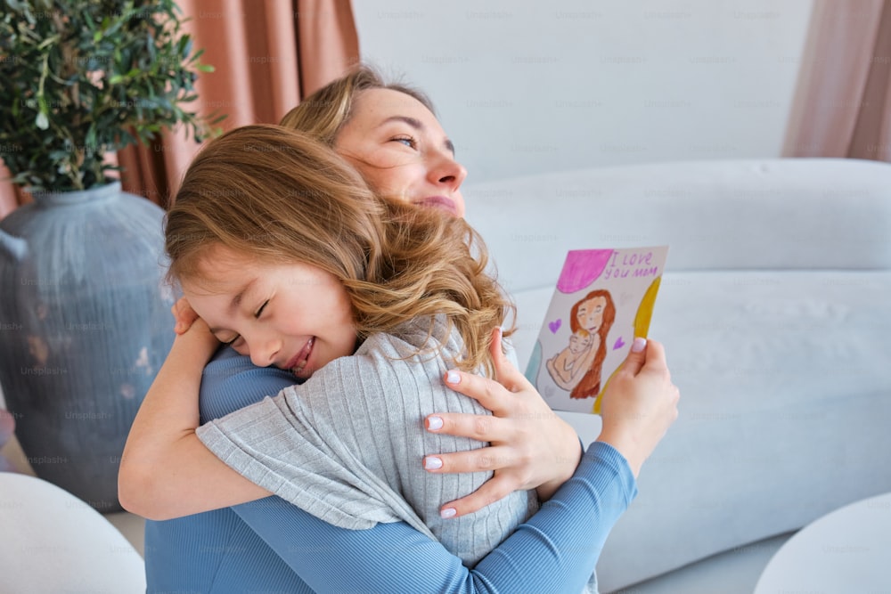 a woman hugging a little girl with a book