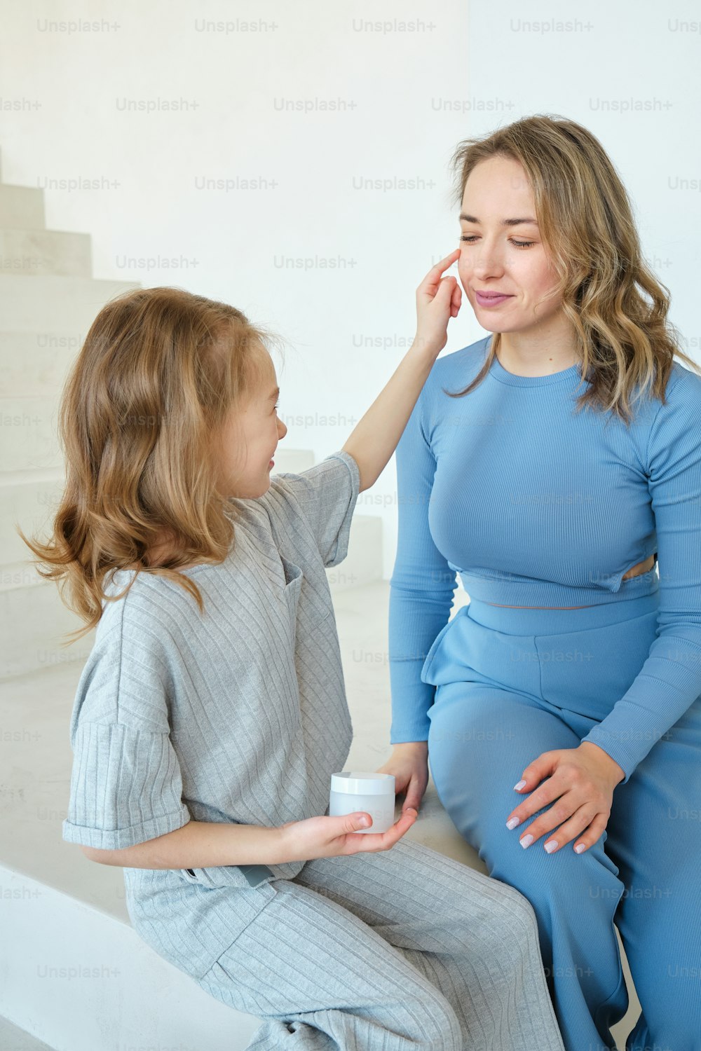 a woman sitting next to a little girl