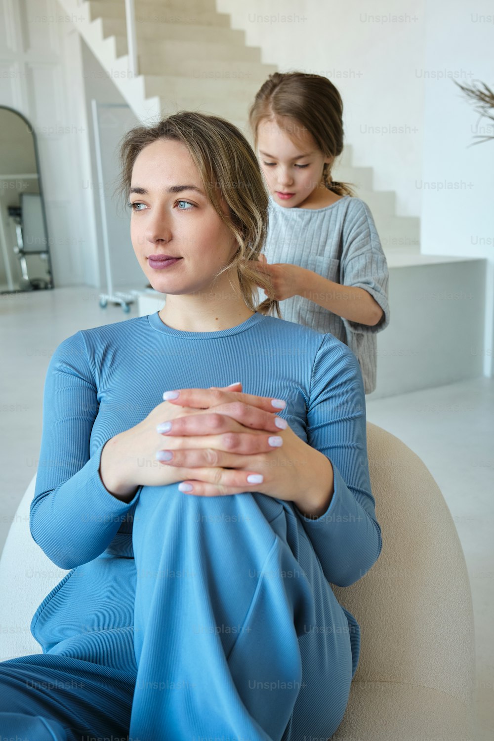 a woman sitting on top of a couch next to a little girl