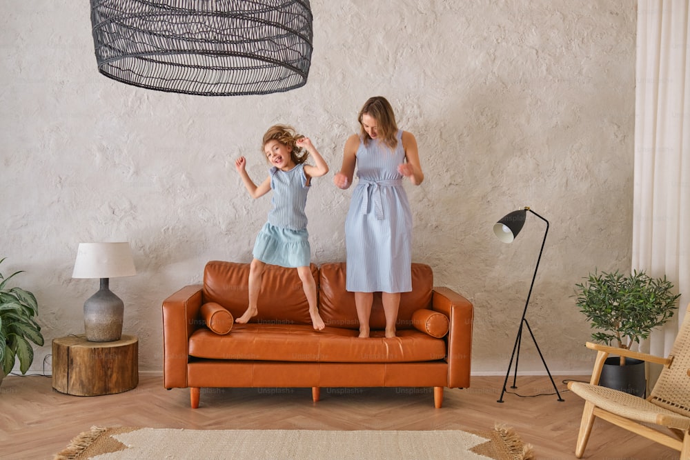 two young girls standing on a couch in a living room