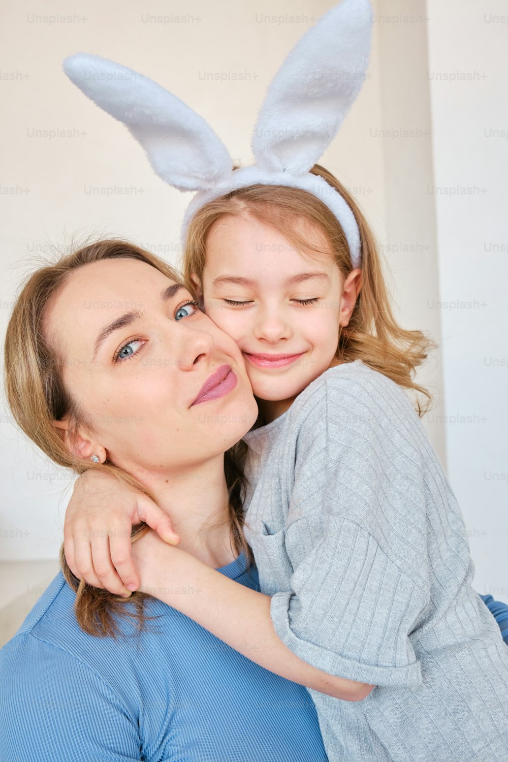 Una mujer abrazando a una niña con orejas de conejo