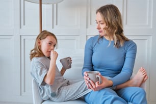 a woman sitting on a couch next to a little girl