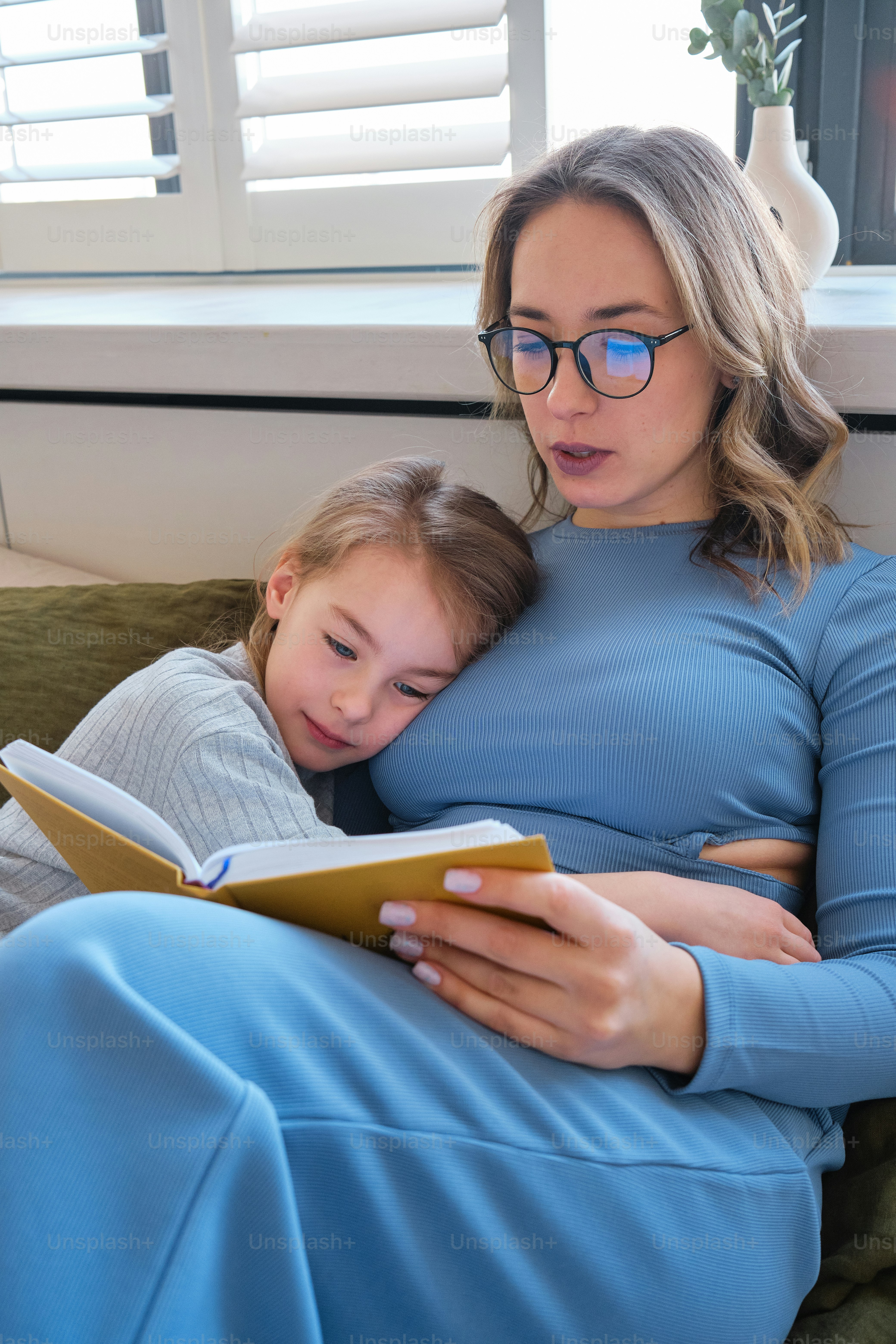 a woman reading a book to a little girl