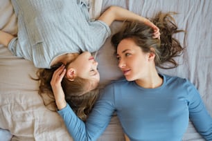 two young women laying on a bed together