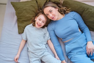 a woman and a child laying on a bed