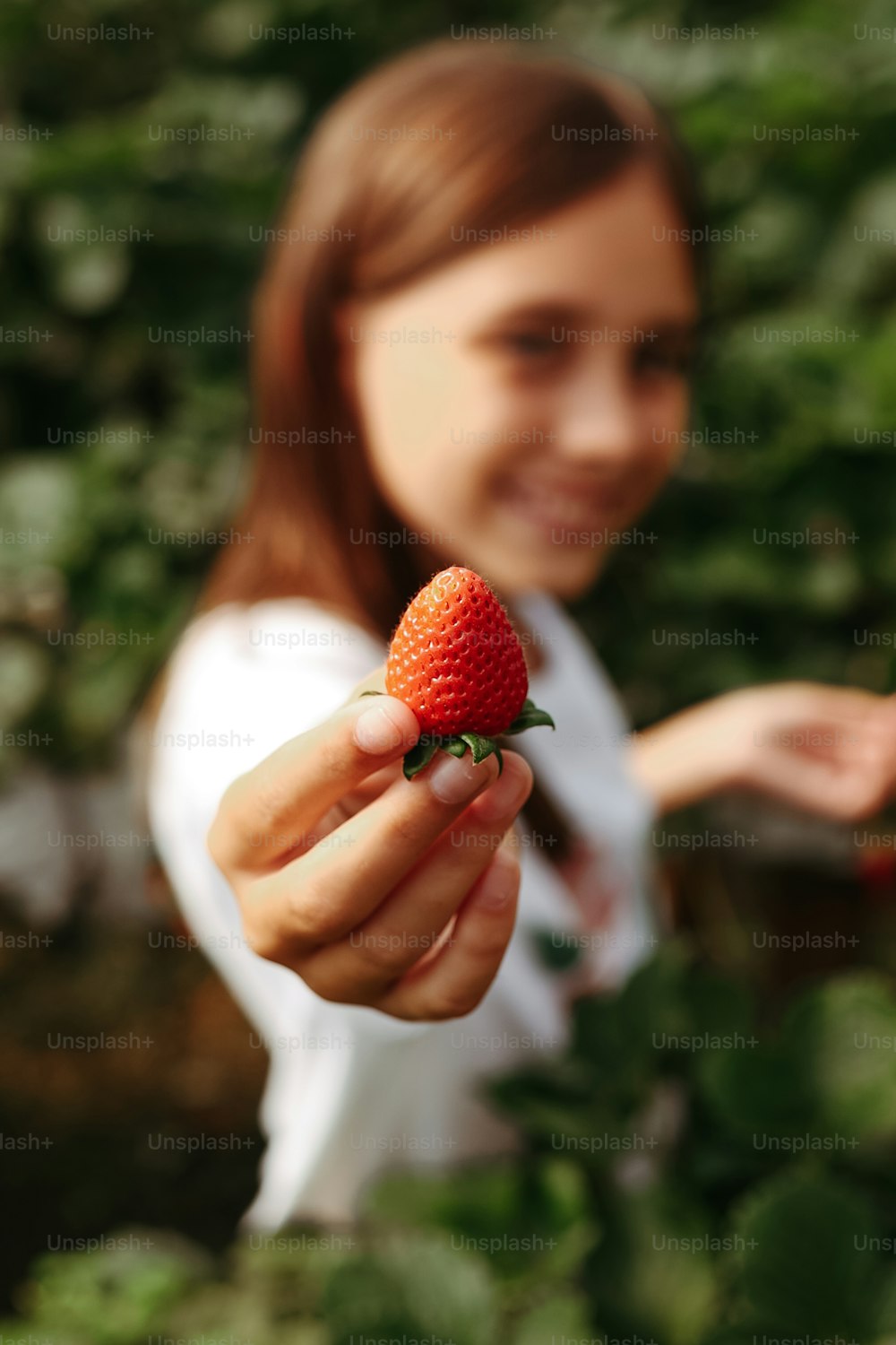 a woman holding a strawberry in her hand