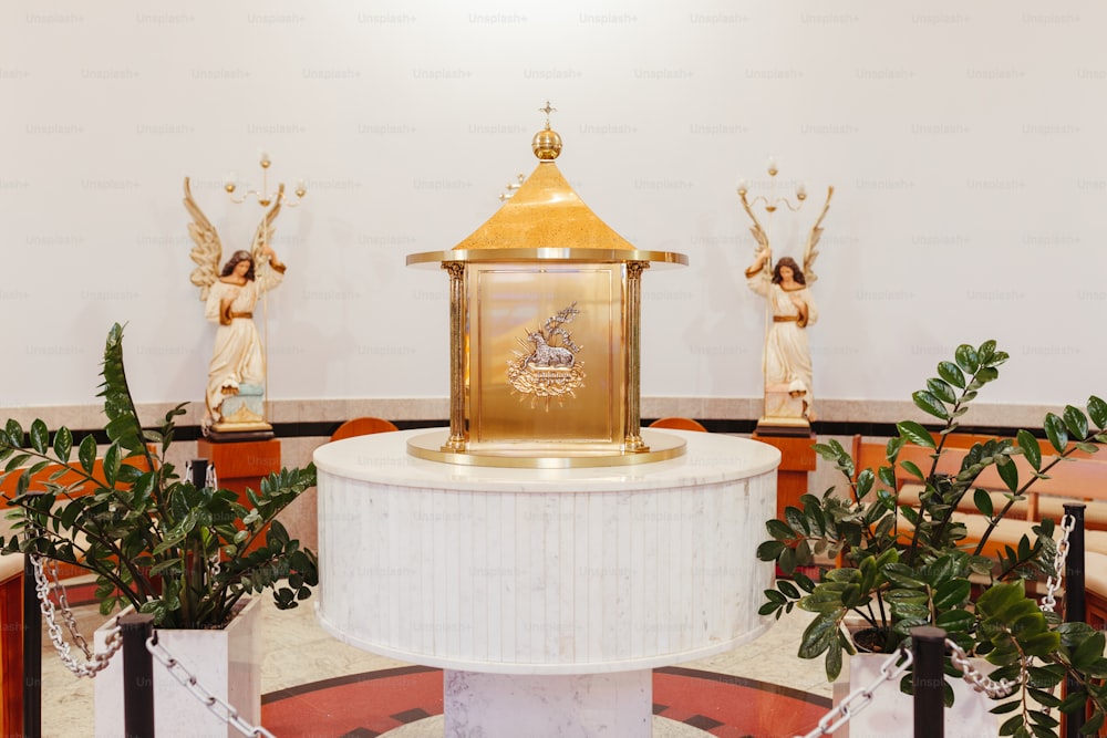 um relógio dourado sentado em cima de um pedestal branco