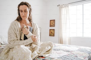 a woman sitting on a bed holding a remote
