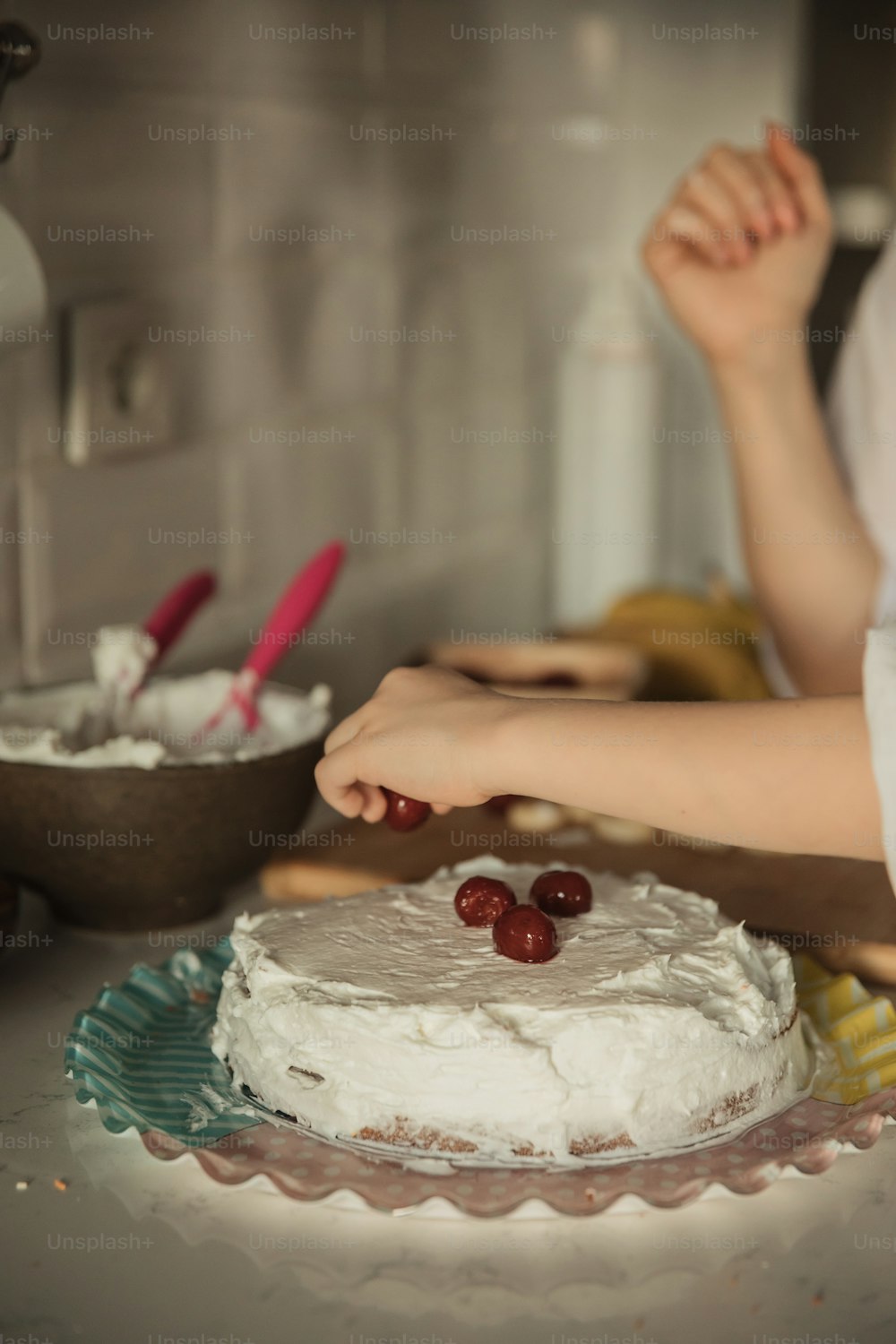 a woman is decorating a cake with cherries