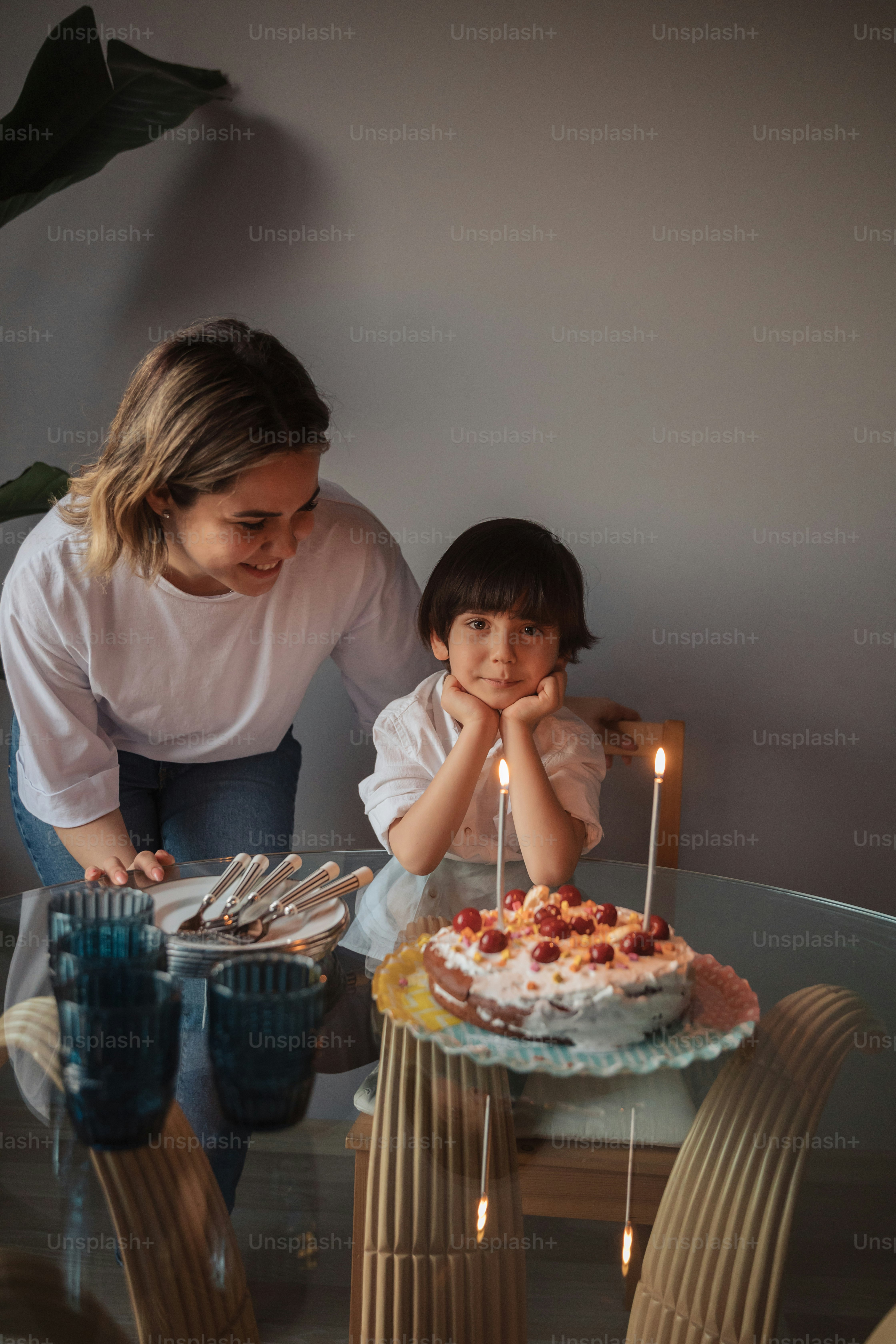 Una mujer y un niño sentados en una mesa con un pastel