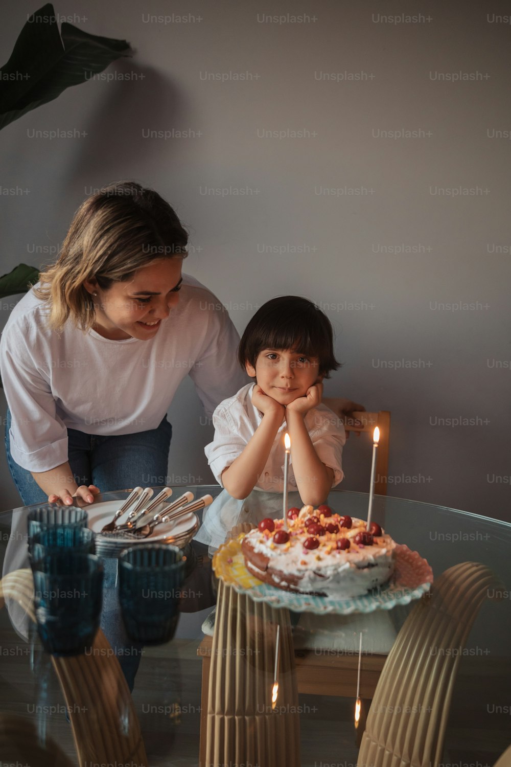 a woman and a child sitting at a table with a cake