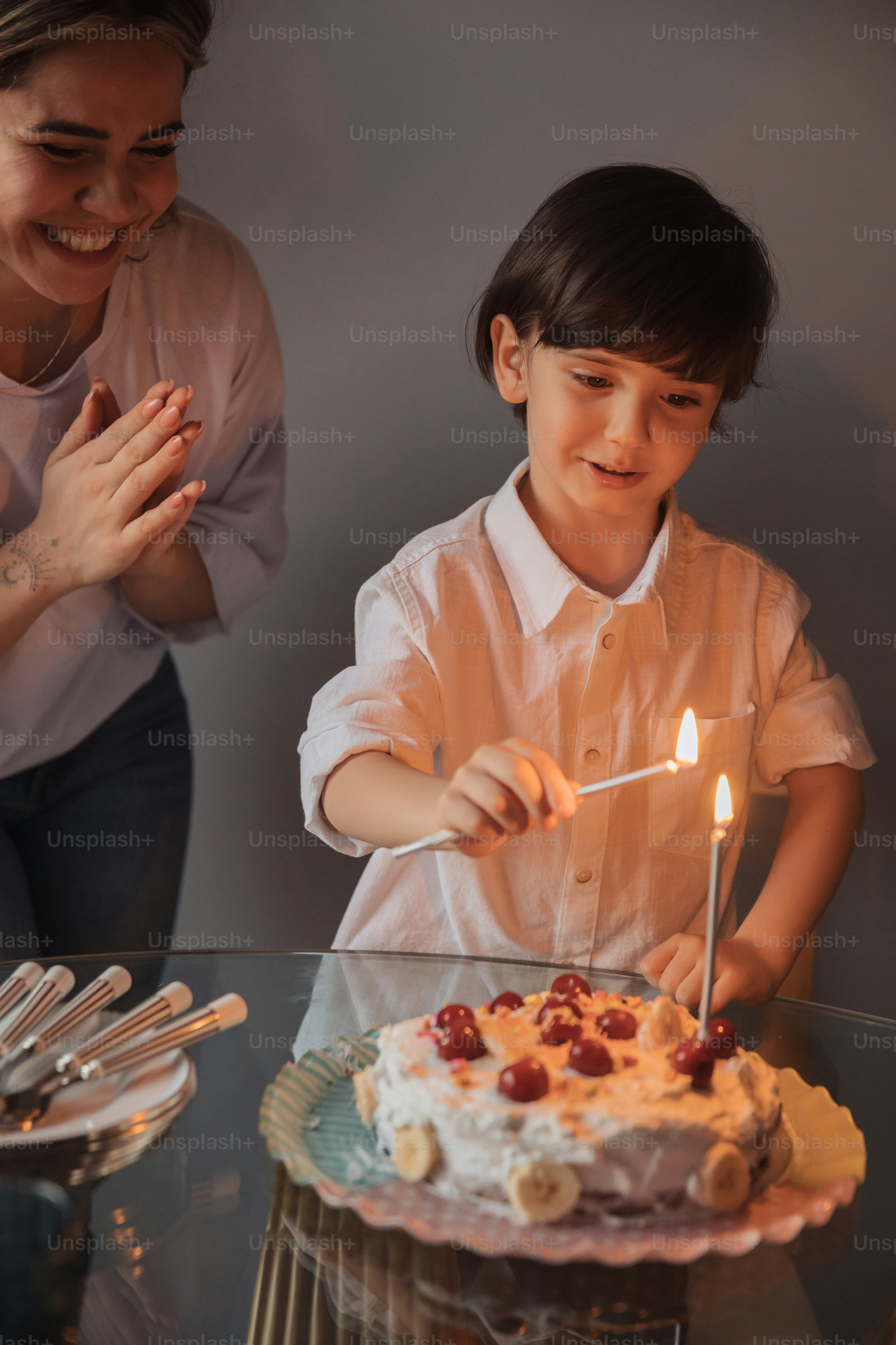 Una mujer y un niño soplando velas en un pastel
