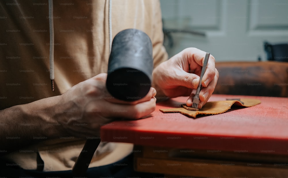 a person cutting a piece of leather with a knife