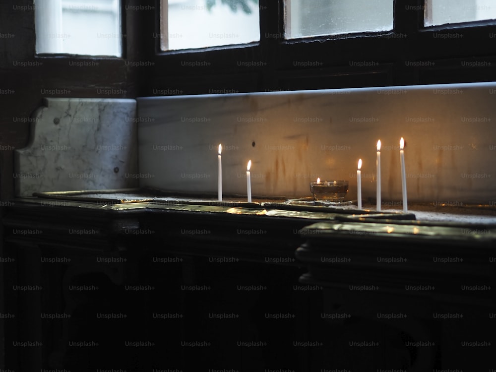 Una fila de velas encendidas sentadas encima de un mostrador