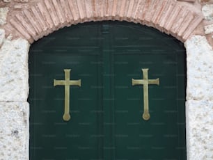 a green door with two gold crosses on it