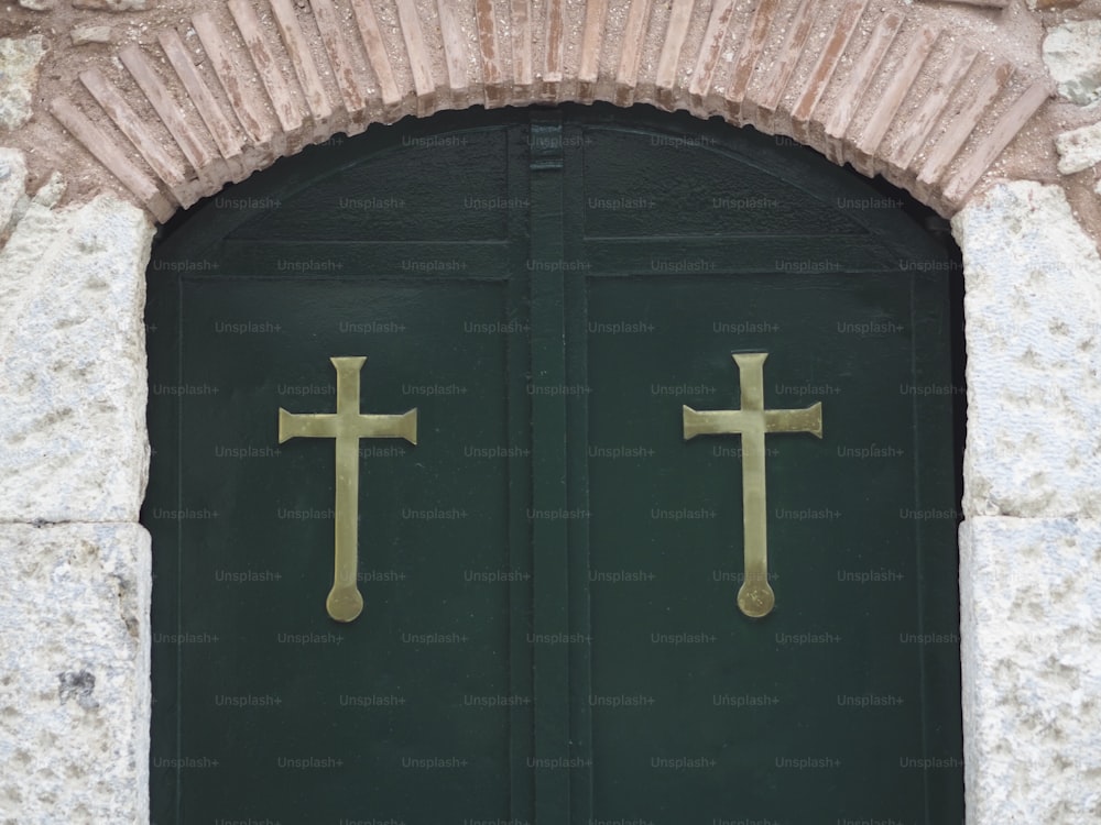 a green door with two gold crosses on it