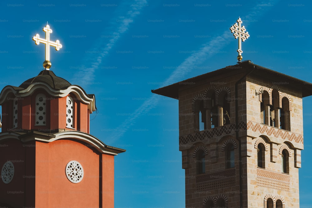 two towers with crosses on top of them against a blue sky