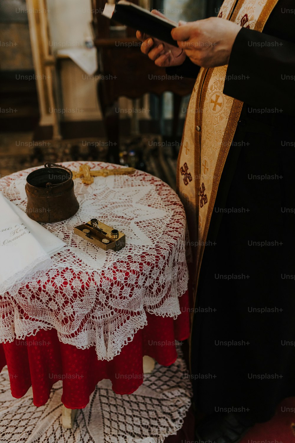 Un prêtre tient une croix et un livre sur une table