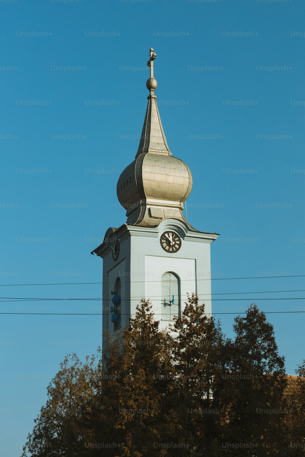 a tall white clock tower with a clock on each of it's sides