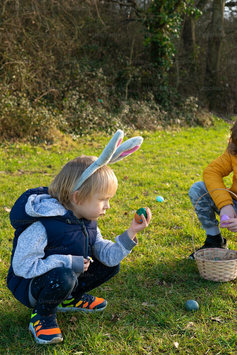 Zwei Kinder spielen mit Ostereiern im Gras