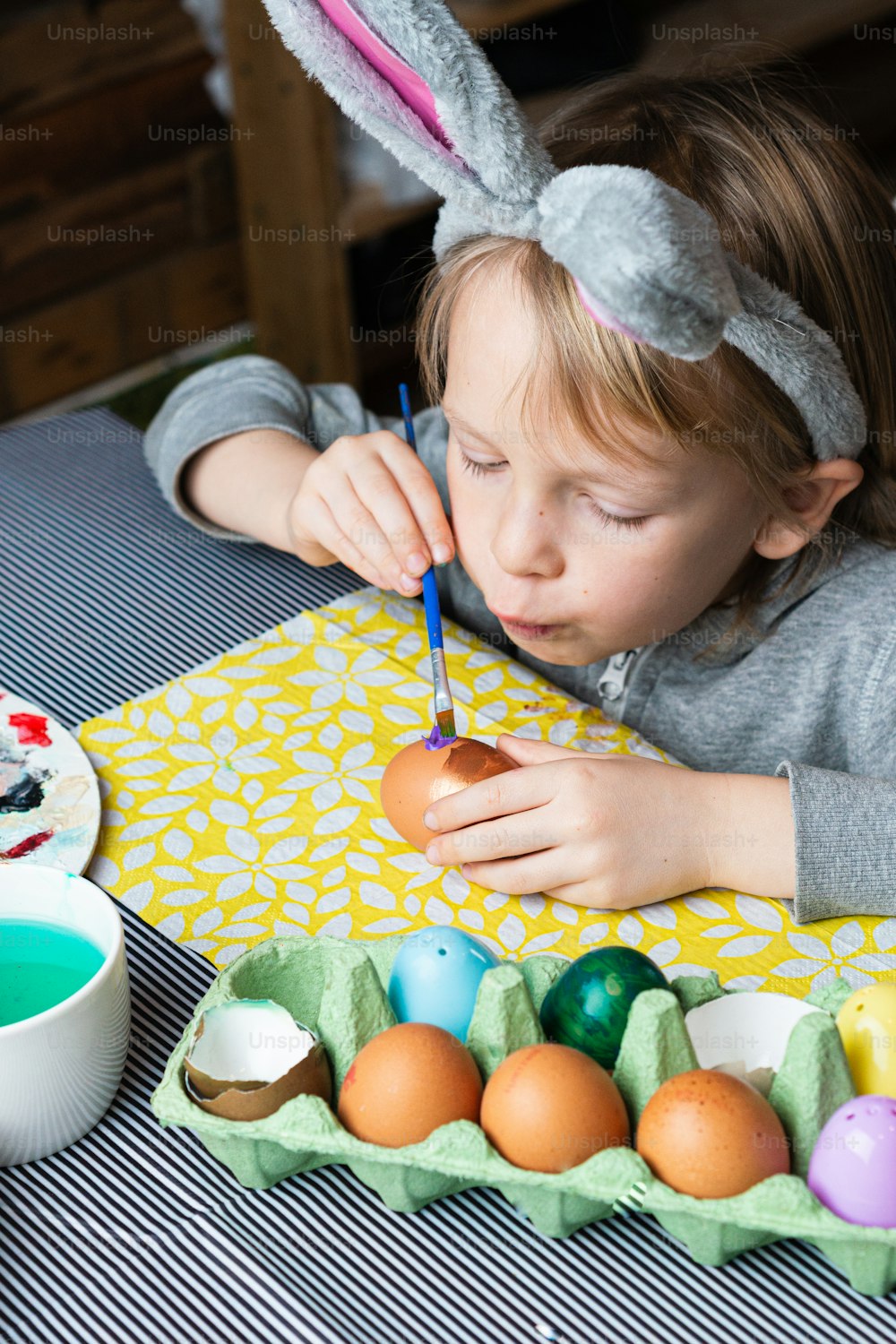 a little girl painting an egg with a brush