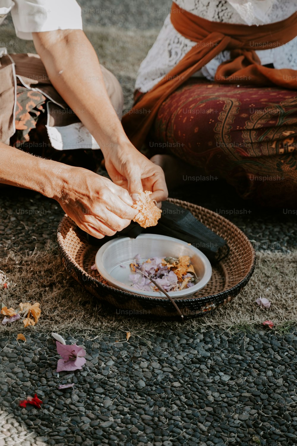 Una persona sentada en el suelo pelando comida de un plato