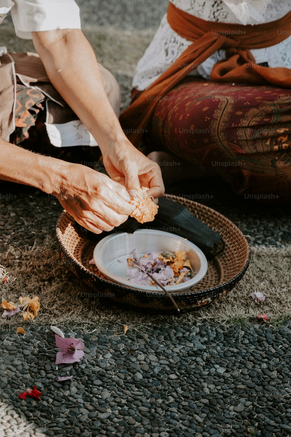 a person sitting on the ground peeling food off of a plate