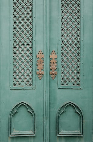 a close up of a green door with ornate designs