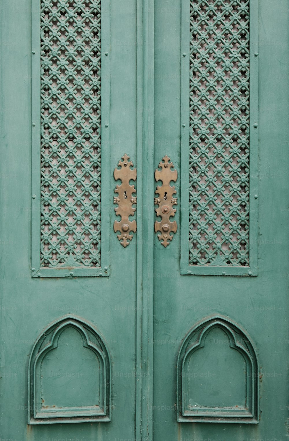 a close up of a green door with ornate designs