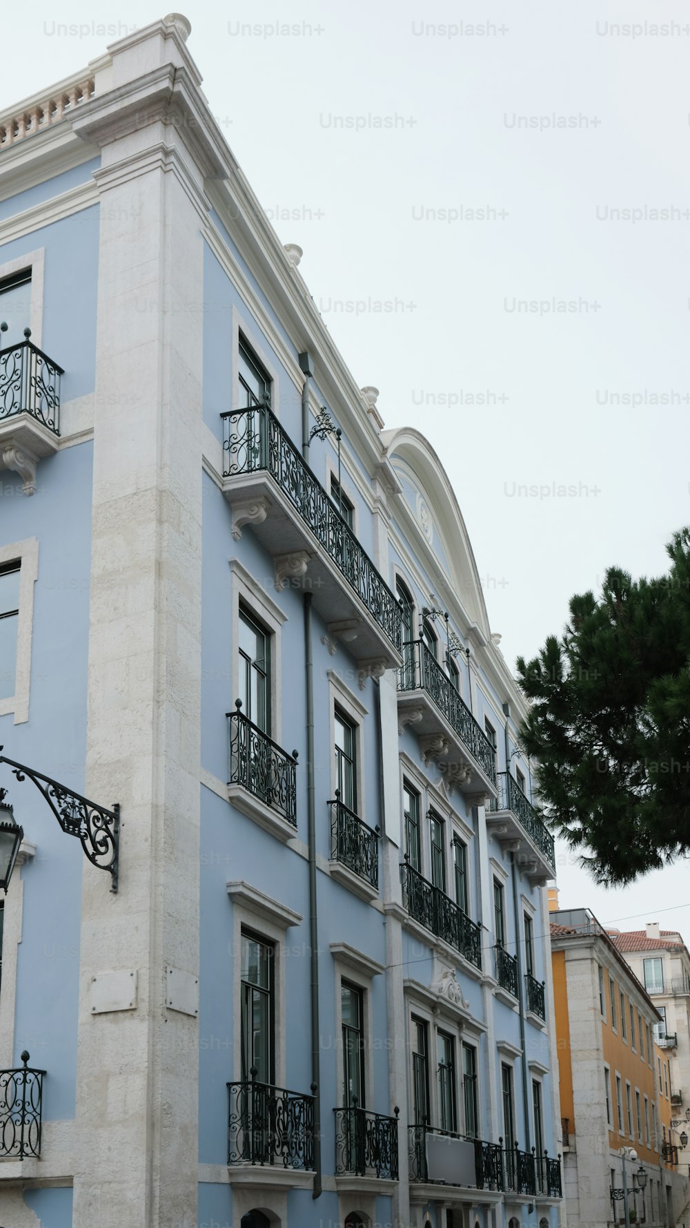 ein blau-weißes Gebäude mit Balkonen und schmiedeeisernen Balkonen