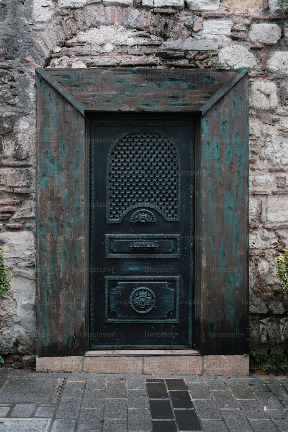 una porta nera con un muro di mattoni dietro di essa