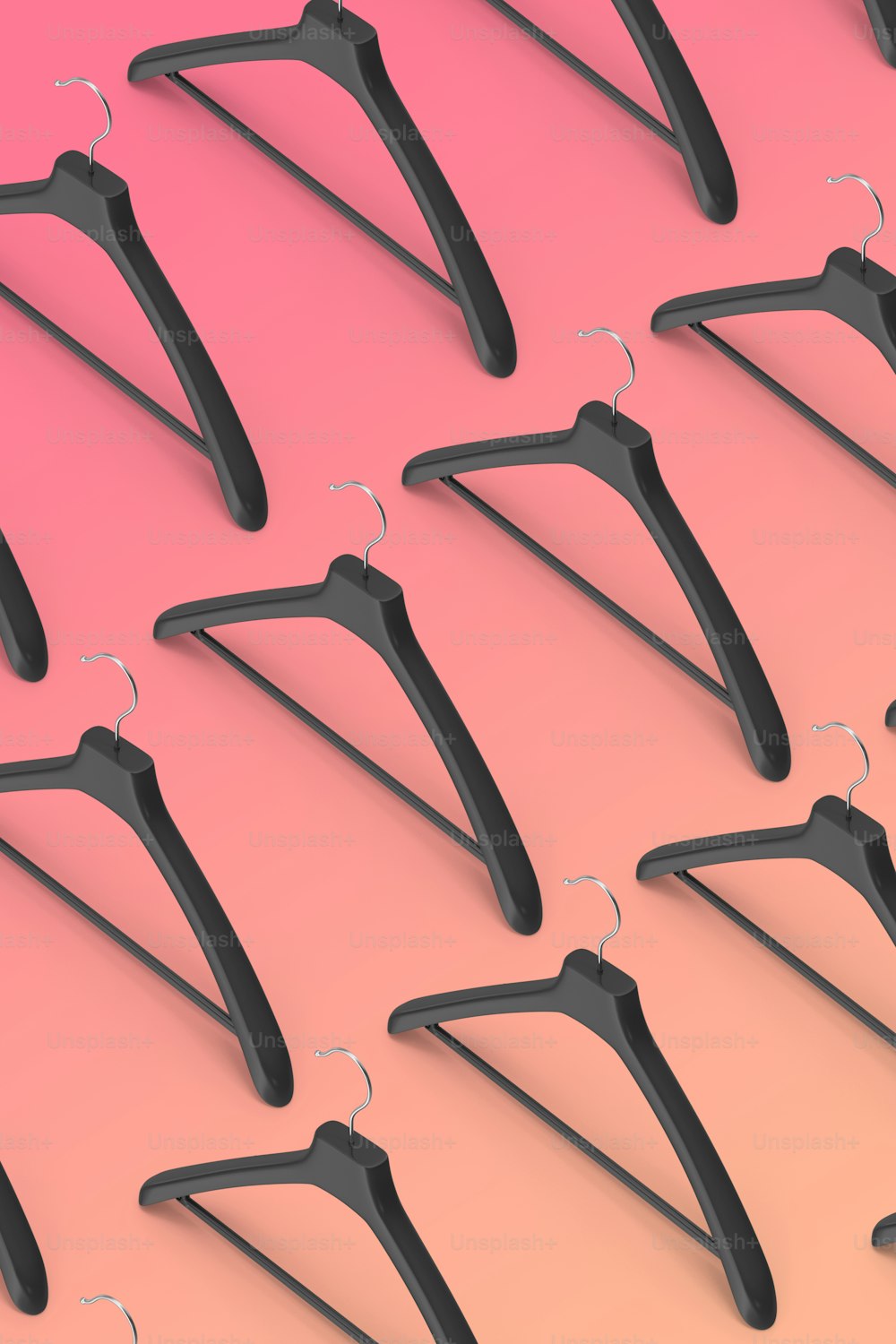 a row of black clothes hangers on a pink and pink background
