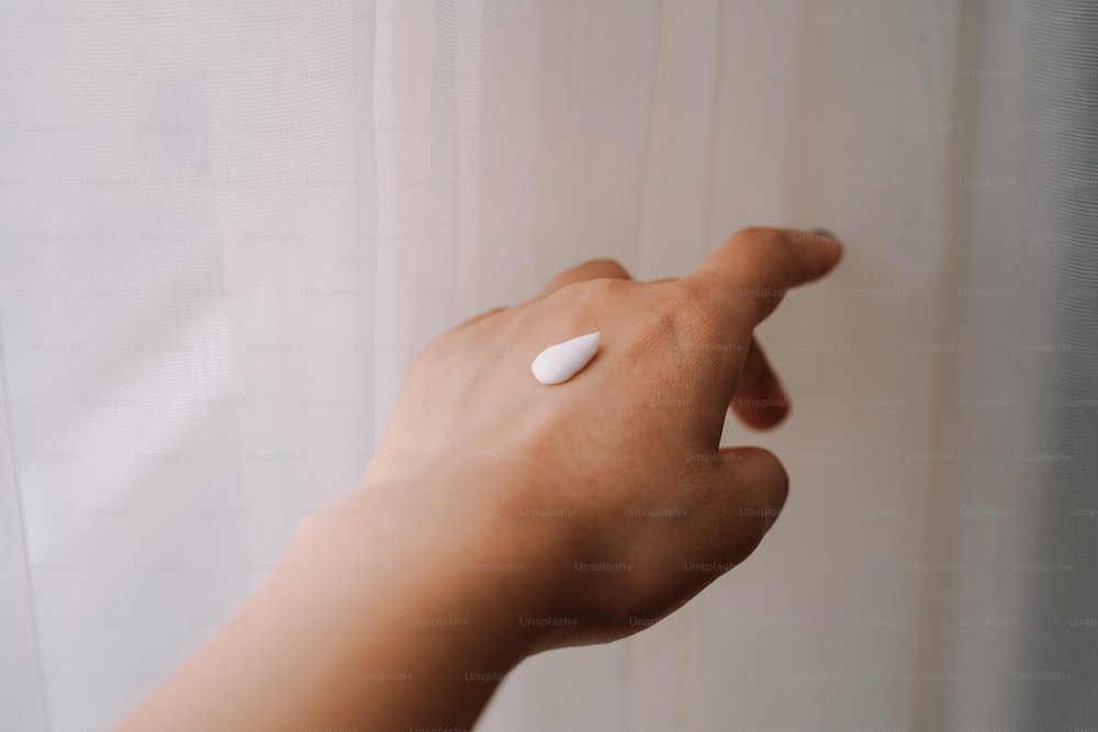 a person's hand with a white pill on it